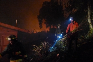 Working with the Forestry Service to clear vegetation away from the house, the glow of the flames clear behind
